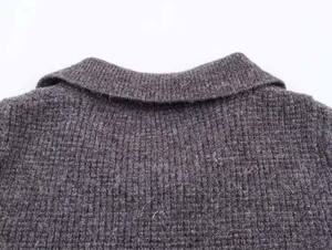 Detail of the knit collar and double-breasted texture on this grey wool sweater