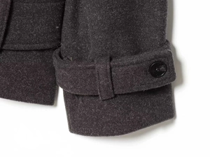 Detailed macro view of charcoal grey wool coat fabric texture and buttoned cuff adjustment