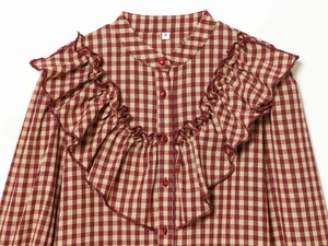 Detail of red gingham shirt featuring ruffled trim and small red buttons on cotton fabric