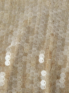 Detail of champagne gold knit fabric with white sequins in a vertical stripe pattern