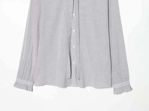 Close-up of ruffled cuffs and white buttons on a gray and white striped cotton shirt