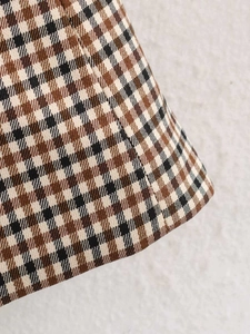 Dettaglio del tessuto a quadri marrone e beige con cuciture pulite e trama fine