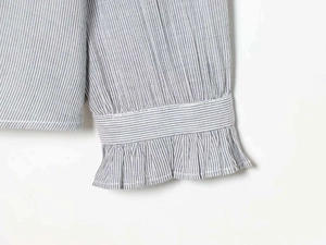 Close-up of ruffled cuffs and fine grey stripes on this minimalist cotton shirt