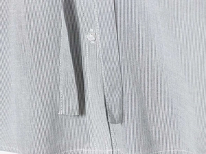 Macro view of blue pinstripe shirt featuring transparent button and detailed stitching