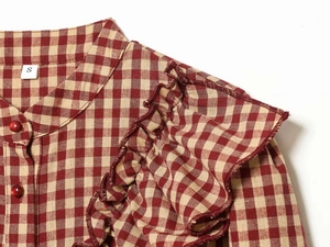 Detail of red gingham shirt showing ruffled shoulders and a small red ball button