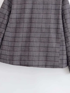 Close-up detail of the fine plaid woven texture and hem stitching of the vintage blazer
