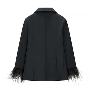 Detail view of black slim-fit blazer sleeves featuring luxury black feather trim accents