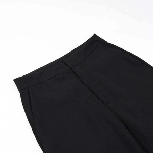 Detail showing the clean high-waisted tailoring and zip fly of these black suit trousers