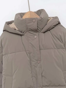 Dettaglio del piumino con cappuccio color taupe, collo alto e bottoni a pressione