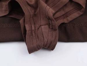 Detaillierte Nahaufnahme von dunkelbraunem Strickstoff mit verstärkter Flachnaht