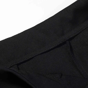Detailed close-up of premium black twill fabric stitching on high-waist suit trousers