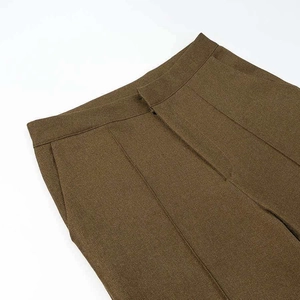 Detailed view of dark olive tailored trousers featuring side pockets and sharp center crease