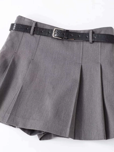 Close-up of grey pleated high-waisted mini skirt with black faux leather belt and silver buckle