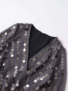 Detailed view of grey V-neck top featuring vertical rows of metallic bronze and silver sequins