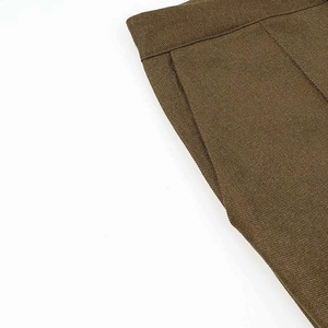 Detail of solid color formal trousers showing waist stitching and side pocket craftsmanship