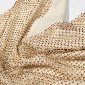 Détail rapproché du tissu en maille pailleté champagne doré avec strass brillants