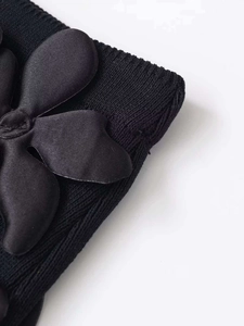 Gros plan d'une jupe en maille noire avec une applique de fleur en satin délicate