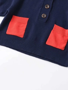 Detail of dark blue knit cardigan with red square pockets and wooden buttons closeup