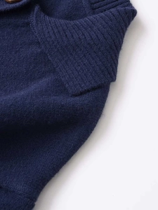 Detail of soft dark blue knit sweater showing ribbed collar and textured brown button