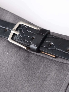 Close-up of black crocodile-embossed leather belt with silver square metal buckle details