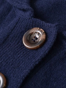 Detailed close-up of a brown faux-tortoise button on dark blue knit fabric