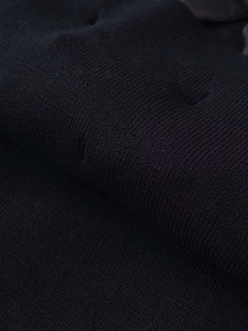 Gros plan du tissu en maille noire montrant la texture premium et le motif côtelé