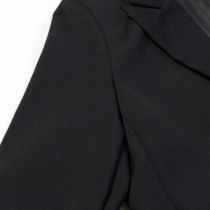 Detailed close-up of premium black blazer shoulder stitching and sharp lapel texture