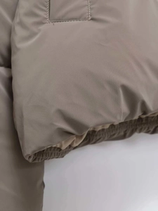 Dettaglio della giacca kaki con cappuccio con cuciture e bordo inferiore elastico