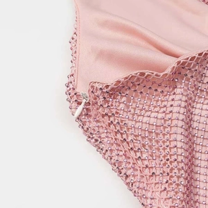 Detail of pink fabric with purple rhinestone mesh and a white invisible zipper closure