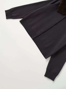 Detail of dark grey knit cardigan featuring a detachable faux fur collar and ribbed cuffs
