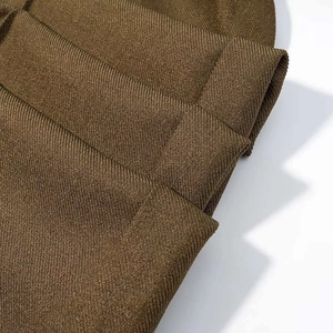 Detailed macro view of dark brown twill fabric texture and fine stitching on the garment