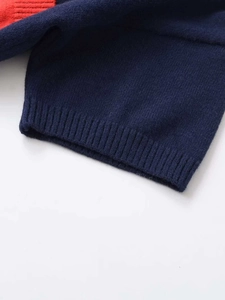 Detailed close-up of dark blue knit sweater with red contrast trim and ribbed cuffs