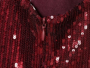 Detail van bordeauxrode paillettenjurk met focus op de onzichtbare ritssluiting en glans