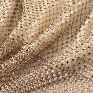 Vue macro détaillée du tissu en maille doré champagne avec strass scintillants pour robe