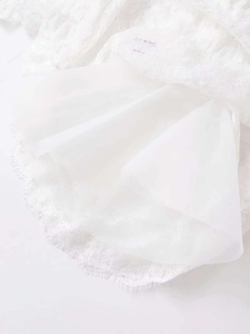 Détail d'un chemisier d'été blanc montrant de la dentelle délicate et un tissu transparent