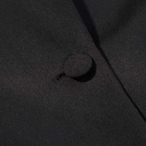 Detail of black twill fabric blazer featuring a matching fabric-covered button and texture