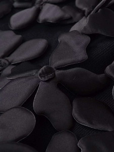 Détail macro de la fleur 3D sur le tissu en satin noir d'une jupe en maille