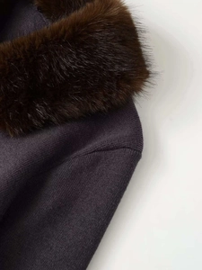 Close-up of fluffy brown faux fur collar on dark knit cardigan with fine texture