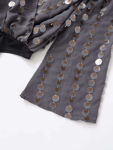 Detail of grey fabric with colorful sequin embroidery and black ribbed cuffs