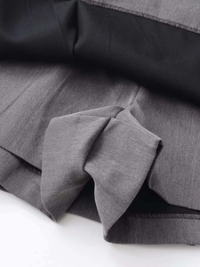 Macro shot of dark grey fabric texture with black inner lining and neat stitched hem detail