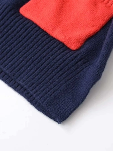 Detail of loose-fit knit top featuring contrast color ribbed hem and soft fabric texture