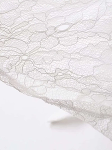Gros plan sur un tissu en dentelle blanche avec broderie florale et détails ajourés