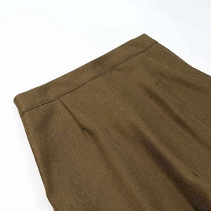 Detailed view of olive brown twill trousers with pleated front and waistline texture