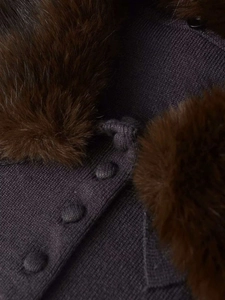 Close-up of deep purple knit cardigan featuring a textured faux fur collar and matching buttons