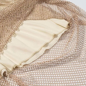 Gros plan sur tissu en maille champagne avec strass dorés et détails de couture finis