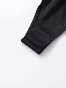Detailed close-up of the black bodysuit bottom featuring secure snap button closures
