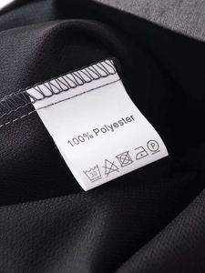 Close-up of garment care label showing 100% polyester material and washing icons