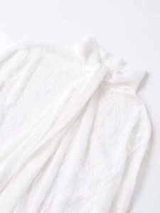 Gros plan détaillé des motifs floraux en dentelle blanche et de la texture du tissu du chemisier
