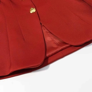Detailed close-up of dark red blazer showing premium twill fabric and gold textured button