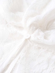 Détail de tissu en dentelle blanche avec motifs floraux et rubans délicats à nouer